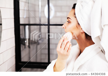 Pretty woman doing cosmetic procedures to care for face skin in bathroom Pretty woman doing cosmetic procedures to care for face skin in bathroom 64364308