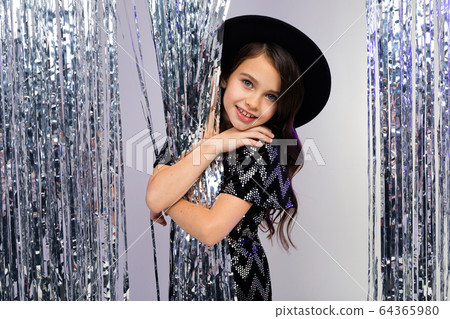 sunny teenage girl in a black hat and elegant dress posing at a party on a shiny background 64365980