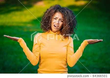 Unsure african american woman shrugs her arms, makes gesture of I don't know, care, can't help 64366501
