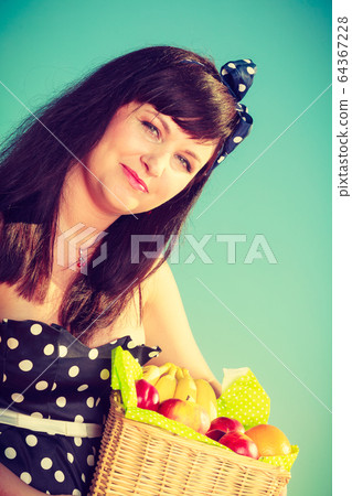 Woman holding picnic basket with fruits 64367228