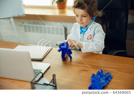 Little caucasian boy as a doctor consulting for patient, working in cabinet, close up 64369003