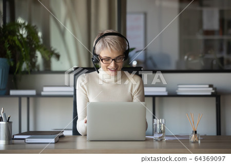 Smiling businesswoman have video call working in office Smiling businesswoman have video call working in office 64369097