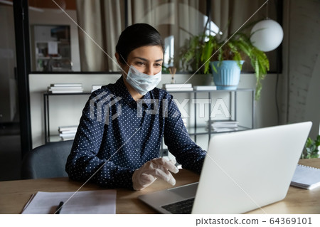 Female employee in mask and rubber gloves working in office 64369101