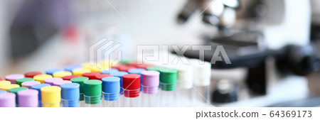 Test tube with colored caps next to microscope 64369173