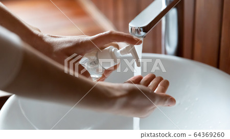 Close up of person cleanse hands with antibacterial soap 64369260