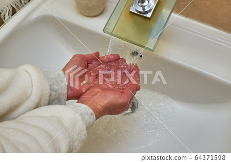 Washing hands over a sink 64371598