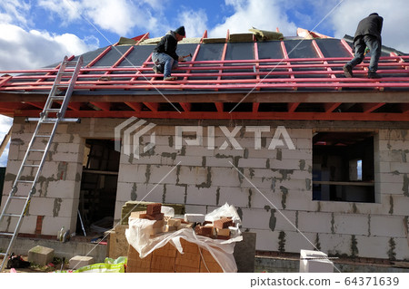 Workers cover the roof with insulating material, 64371639