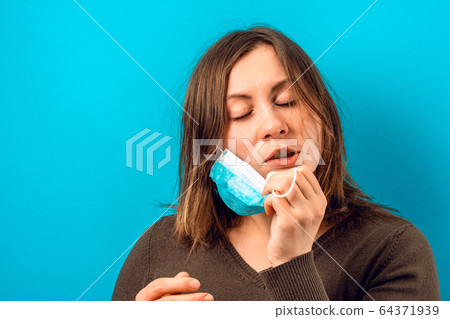 Portrait of a woman dissatisfied with a mask on a blue background. Portrait of a woman dissatisfied with a mask on a blue background. 64371939