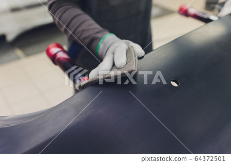 Auto mechanic preparing the car for paint job by applying polish with the power buffer machine Auto mechanic preparing the car for paint job by applying polish with the power buffer machine 64372501