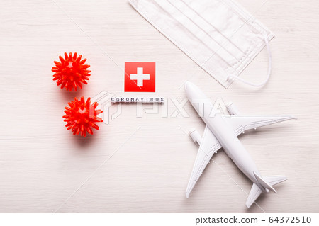 Plane model and face mask and flag Switzerland. Coronavirus pandemic. Flight ban and closed borders for tourists and travelers with coronavirus covid-19 from Europe and Asia. Plane model and face mask and flag Switzerland. Coronavirus pandemic. Flight ban and closed borders for tourists and travelers with coronavirus covid-19 from Europe and Asia. 64372510