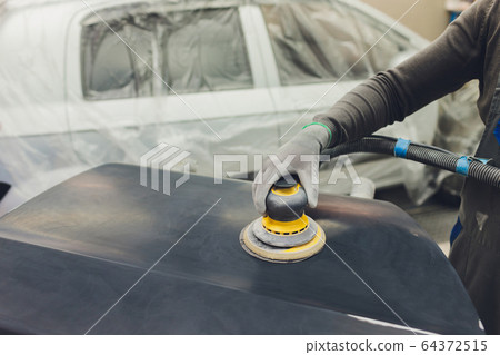 Auto mechanic preparing the car for paint job by applying polish with the power buffer machine Auto mechanic preparing the car for paint job by applying polish with the power buffer machine 64372515