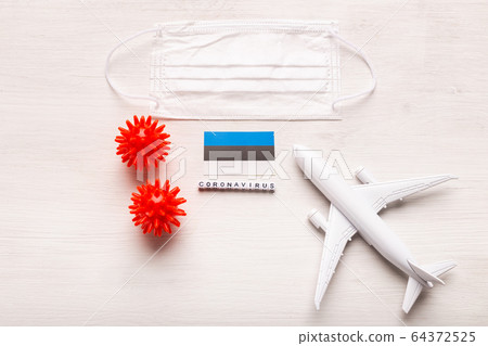 Plane model and face mask and flag Estonia. Coronavirus pandemic. Flight ban and closed borders for tourists and travelers with coronavirus covid-19 from Europe and Asia. 64372525