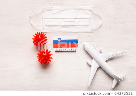 Plane model and face mask and flag Slovenia. Coronavirus pandemic. Flight ban and closed borders for tourists and travelers with coronavirus covid-19 from Europe and Asia. 64372531
