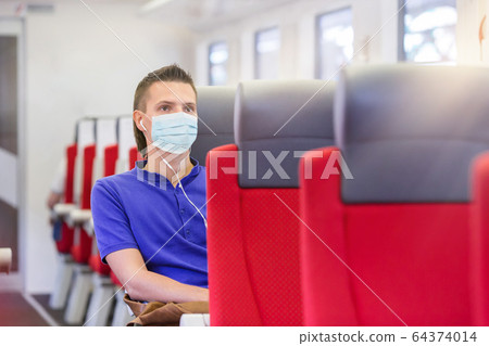 Young man traveling by train and wears a mask 64374014