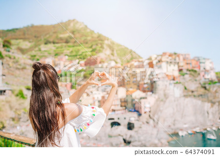 Happy girl making with hands heart shape on the old coastal village in Cinque Terre National Park. Happy girl making with hands heart shape on the old coastal village in Cinque Terre National Park. 64374091