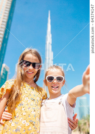 Happy girls walking in Dubai with skyscraper in the background. Happy girls walking in Dubai with skyscraper in the background. 64374147