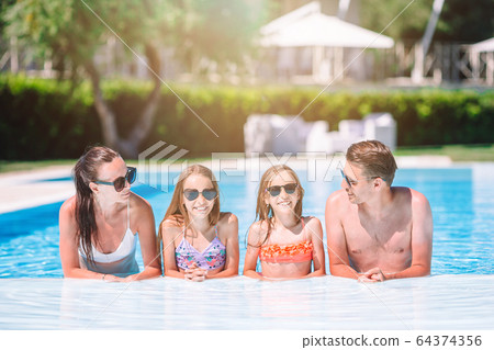 Happy family of four in outdoors swimming pool Happy family of four in outdoors swimming pool 64374356