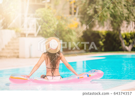 Beautiful young woman relaxing in swimming pool. 64374357