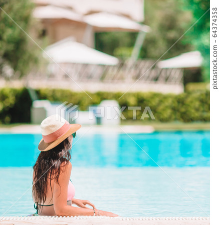Beautiful young woman relaxing in swimming pool. Beautiful young woman relaxing in swimming pool. 64374358