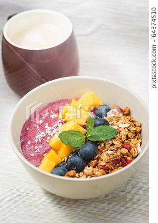 Handmade Bowl healthy tasty breakfast of yogurt, smoothie with granola, nuts, mango and berries. 64374510
