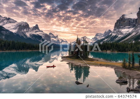 Traveler canoeing with rocky mountain reflection 64374574