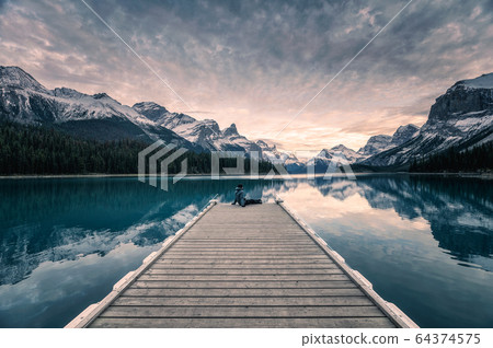Traveler relaxing on wooden pier in Maligne lake 64374575