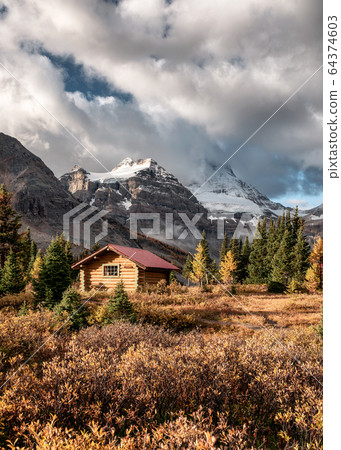 Wooden huts with Rocky mountains in autumn forest 64374603