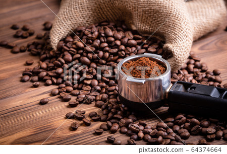 Roasted coffee beans waking up from a jute coffee bag. Roasted coffee beans waking up from a jute coffee bag. 64374664
