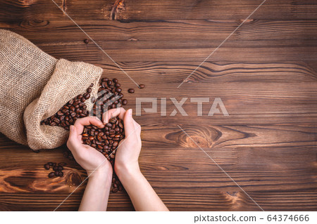 Roasted coffee beans waking up from a jute coffee bag. Roasted coffee beans waking up from a jute coffee bag. 64374666