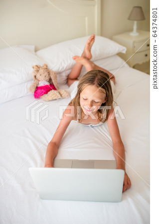Cute little girl doing homework on laptop Cute little girl doing homework on laptop 64374801