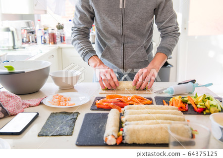 Cropped young caucasian man making sushi at home Cropped young caucasian man making sushi at home 64375125