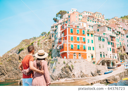 Young tourist couple traveling on european holidays outdoors in italian vacation in Cinque Terre 64376723