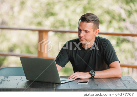 Young man with laptop works from home Young man with laptop works from home 64377707