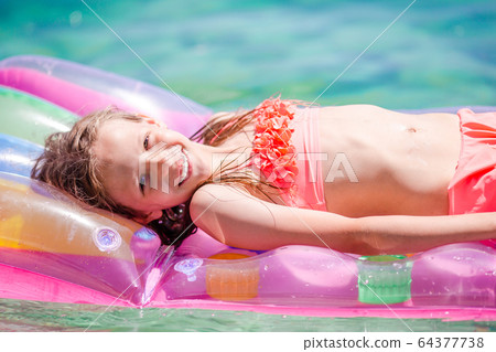 Adorable girl on inflatable air mattress in the sea 64377738