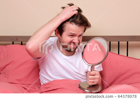 young man looking on mirror looking on his long 64378078