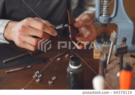 Man in a studio creates leather ware 64378119