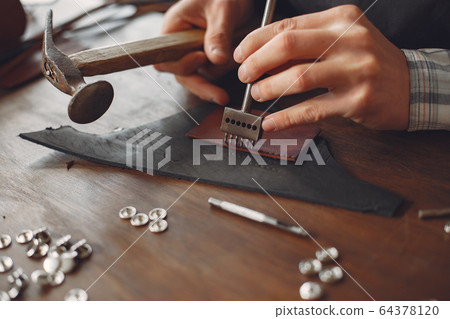 Man in a studio creates leather ware Man in a studio creates leather ware 64378120