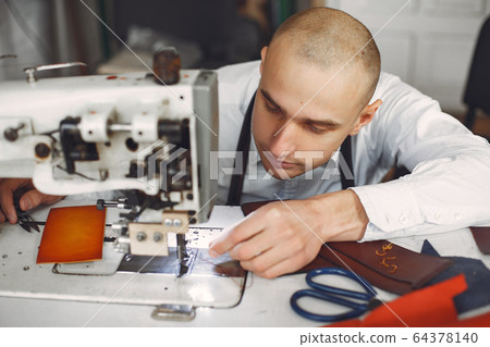 Man in a studio creates leather ware 64378140