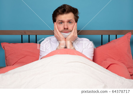 Sick mature caucasian man lying down in bed 64378717