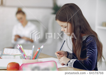 Little girl sitting on a table with books Little girl sitting on a table with books 64378788