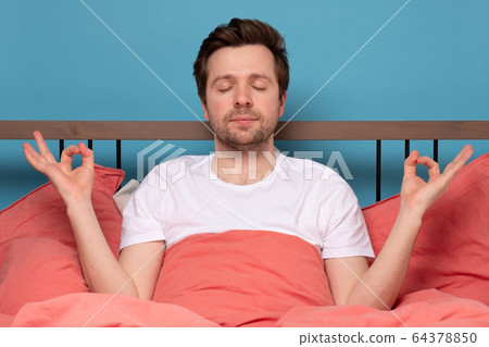 man meditates on quarantine, at the bed, tries to man meditates on quarantine, at the bed, tries to 64378850
