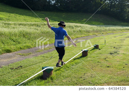 Men playing slackline 64384520