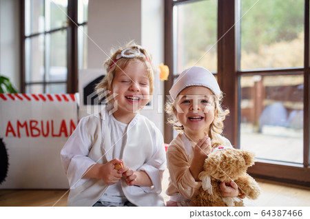 Two small children with doctor uniforms indoors at home, playing. 64387466