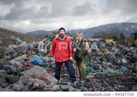 Man and woman hikers on landfill, environmental concept. 64387728