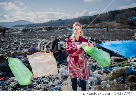 Woman on landfill, consumerism versus plastic pollution concept. 64387744
