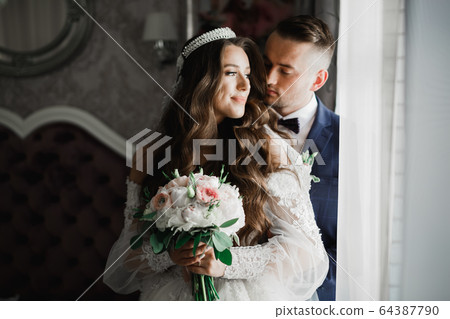 Beautiful young wedding couple posing with bouquet of flowers in hands 64387790