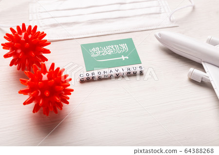 Plane model and face mask and flag Saudi Arabia. Coronavirus pandemic. Flight ban and closed borders for tourists and travelers with coronavirus covid-19 from Europe and Asia. 64388268