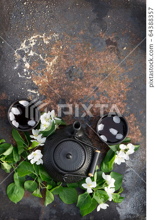 Black ceramic teapot and cup with hot tea 64388357