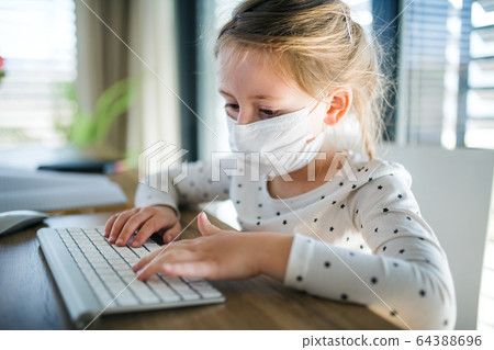 Small girl using computer indoors at home, Corona virus and quarantine concept. Small girl using computer indoors at home, Corona virus and quarantine concept. 64388696