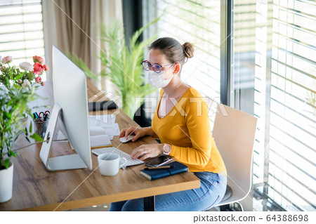 Woman working indoors at home office, Corona virus and quarantine concept. Woman working indoors at home office, Corona virus and quarantine concept. 64388698